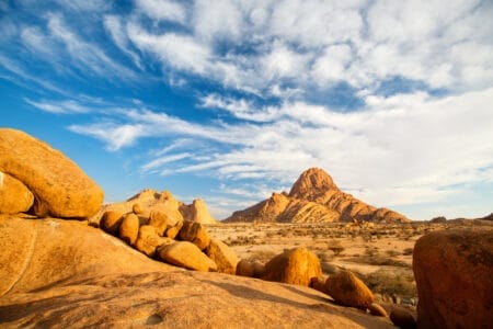 „Wüstenlandschaft in Spitzkoppe, Namibia mit großen runden Felsen und markantem Berg unter blauem Himmel – ideal für Naturreisen und Landschaftsfotografie.“