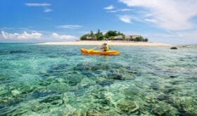 Young woman kayaking near South Sea Island, Mamanuca islands group, Fiji. This group consists of about 20 islands.