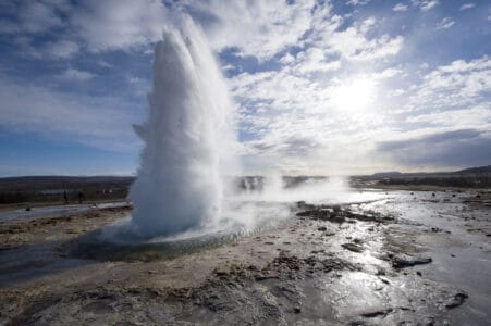 Ein Geysir schießt eine hohe Wasserfontäne in die Luft
