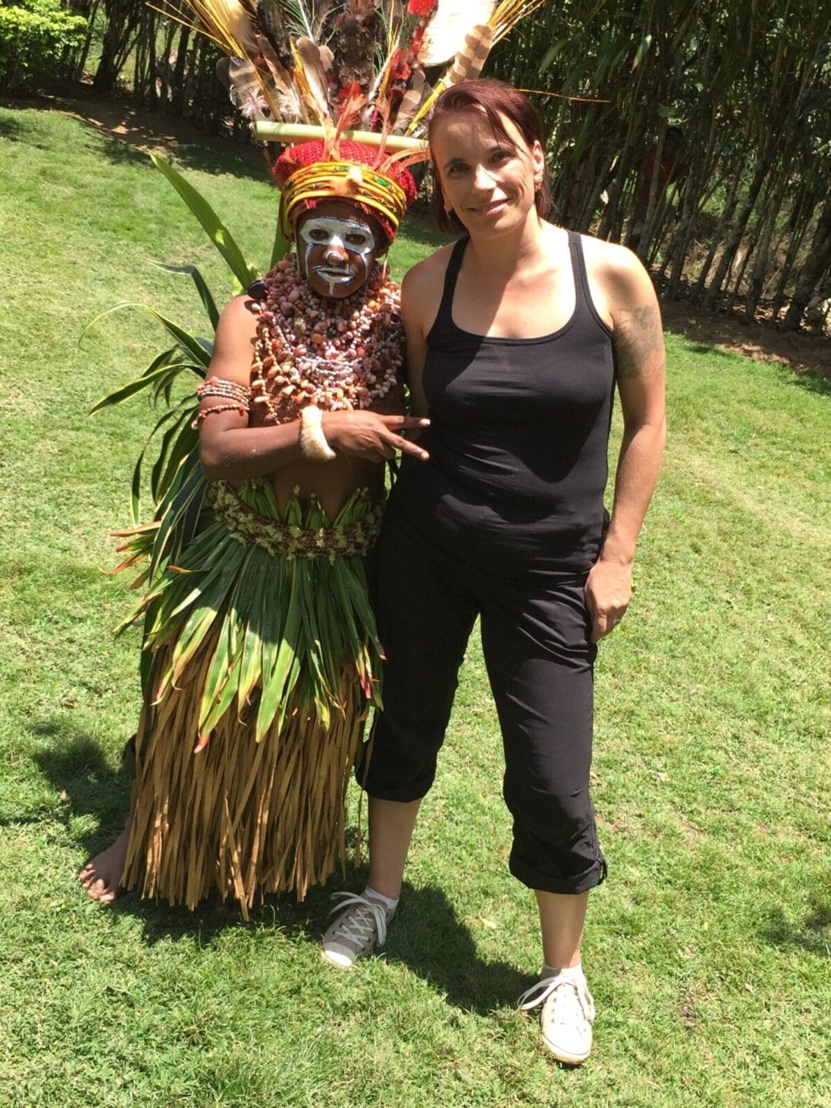 Zwei Personen, auf grüner Wiese, hohe Bäume im Hintergrund