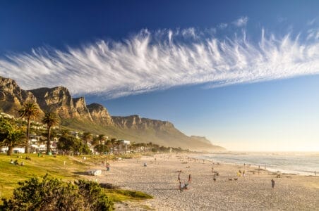 „Strand von Camps Bay in Südafrika mit feinem Sand, entspannter Atmosphäre, grüner Bergkulisse und klarem blauen Himmel – beliebtes Reiseziel für Badeurlaub und Naturerlebnis.“