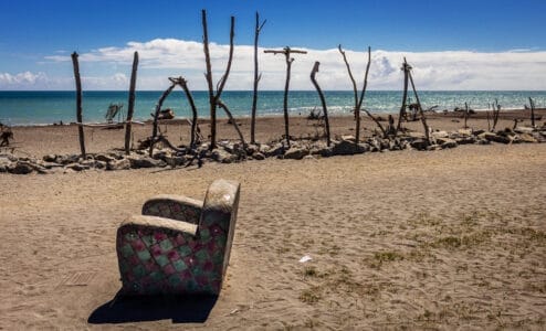 Bunter Sessel am Hokitika Beach vor der Tasmansee, Treibholz-Buchstaben formen „Hokitika“ – Neuseelands Südinsel Westküste.
