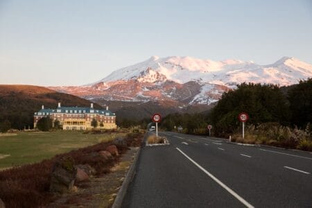 Straße mit Blick auf schneebedeckte Berge im Tongariro‑Nationalpark auf der Nordinsel Neuseelands